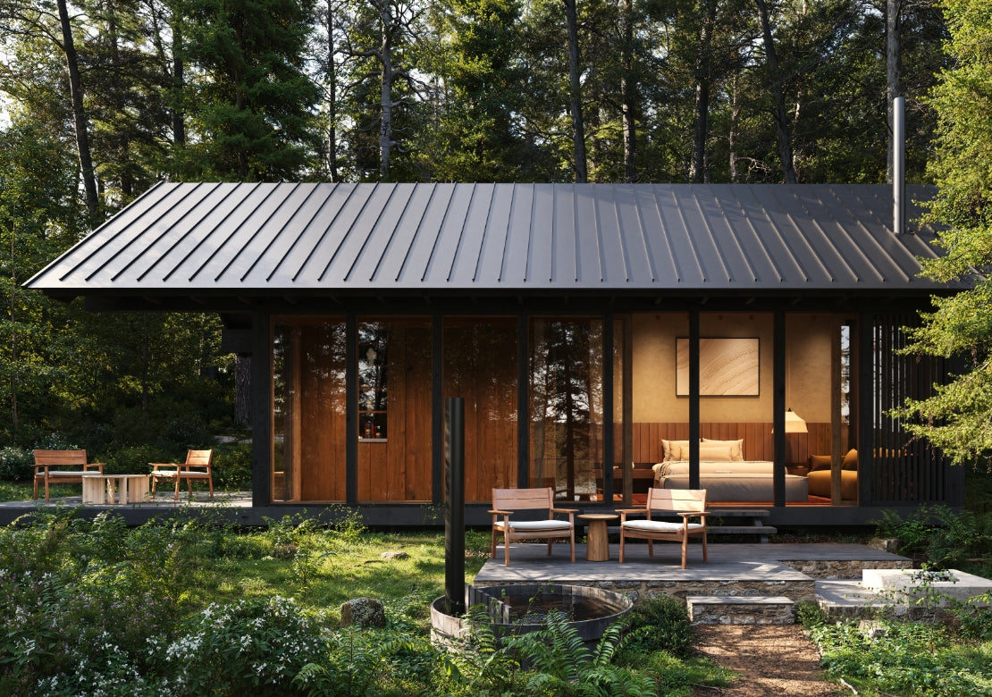 Modern cabin in the woods with a black roof and wooden exterior.