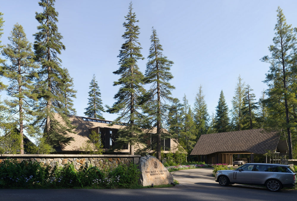Wooden lodge surrounded by tall trees with a clear blue sky