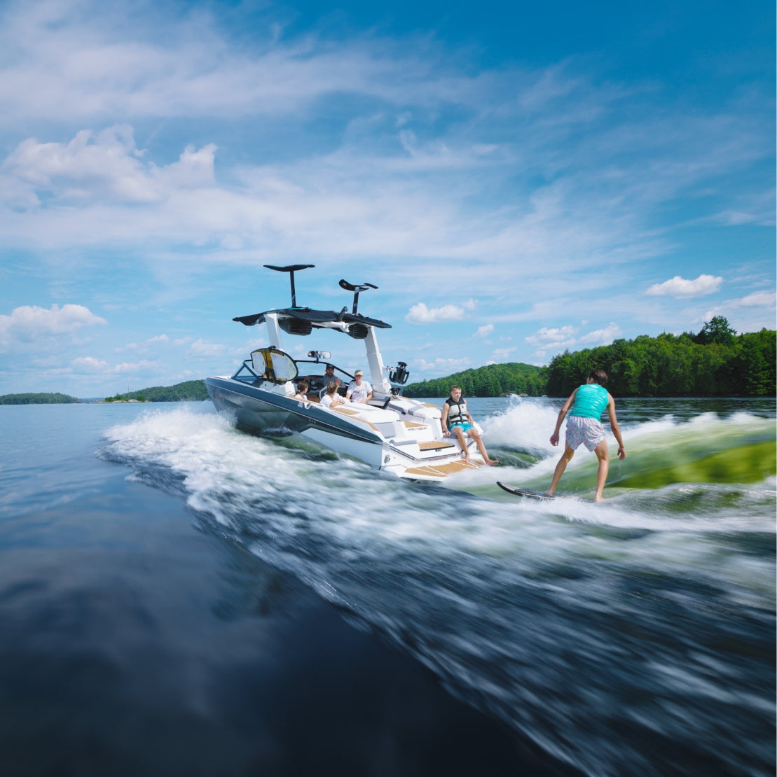 Boat on a lake with people enjoying the water under a clear blue sky.