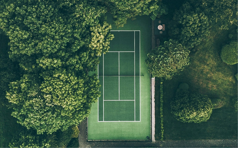 Tennis court surrounded by trees from an aerial perspective